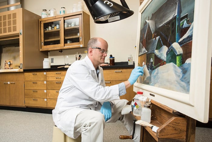 Conservator working on a painting in a workshop studio