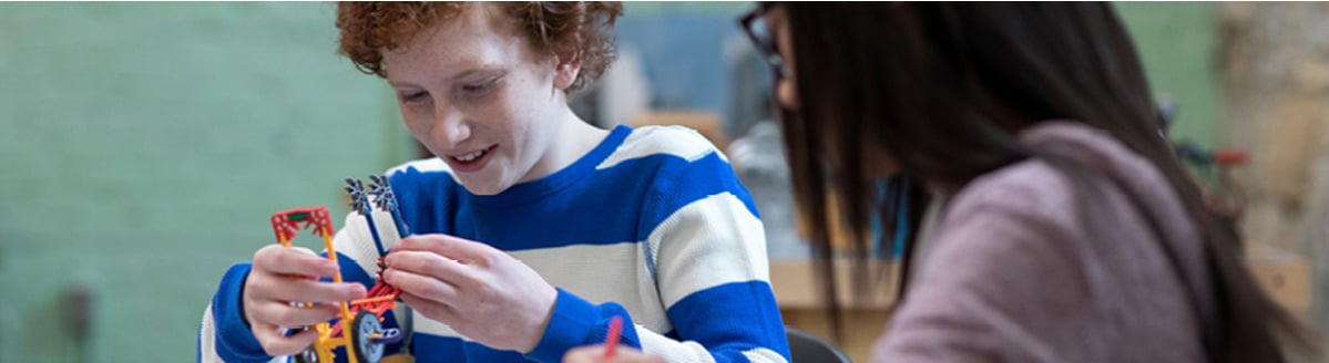 Two children sit and build toys using small parts.